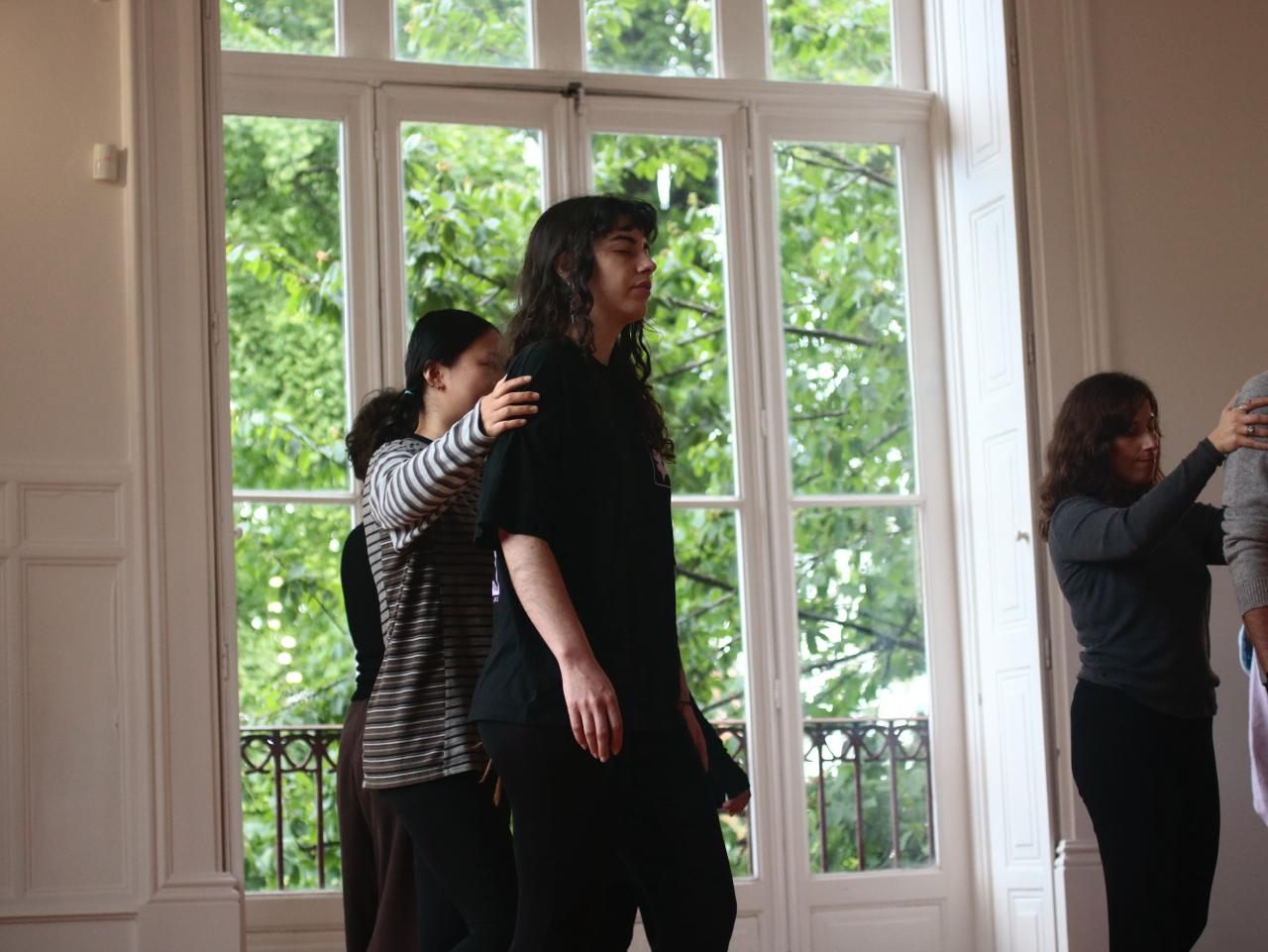 Two participants in a somatic attunement exercise, one hand resting on the other's back