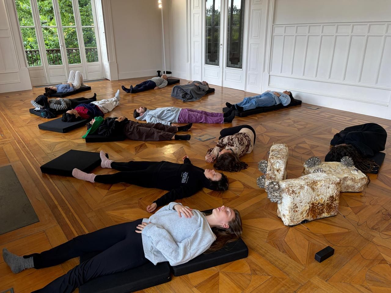 Participants lying in stillness across the floor beside the living sculptures