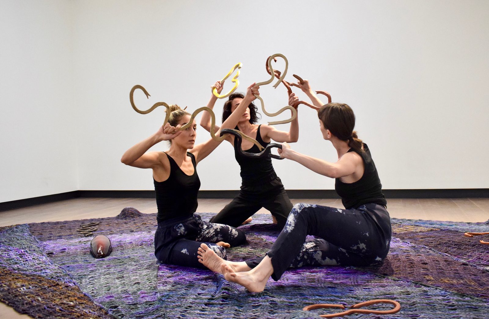 Three performers holding rope forms above their heads