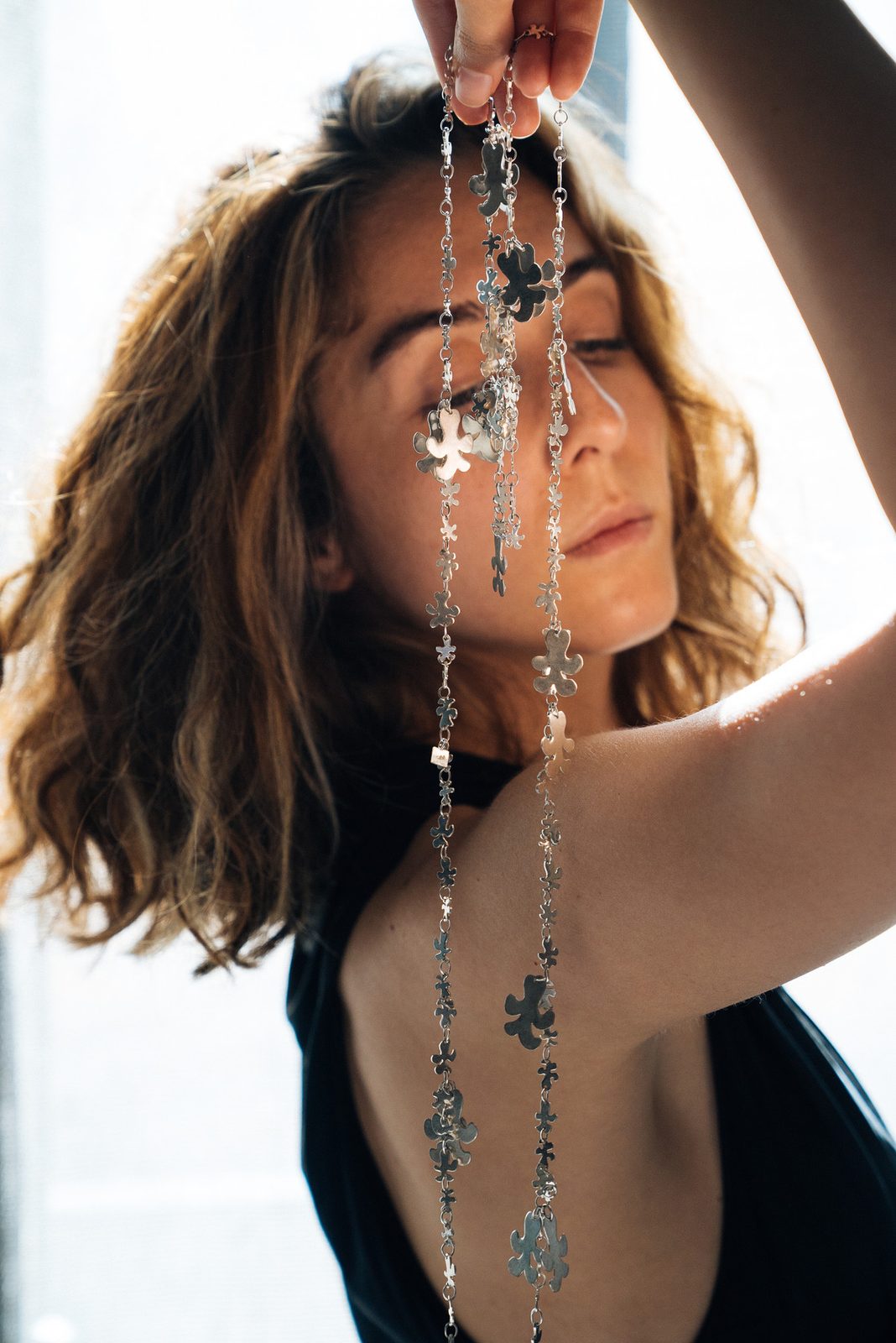 Dila holding a long silver chain up to the light