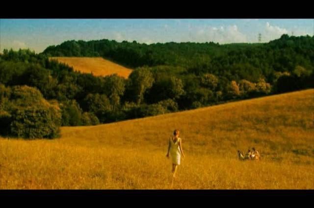A woman in a light dress walking across the meadow, still from the film