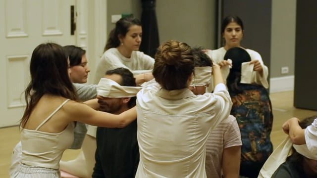 Blindfolded participants guided by performers, still from the video
